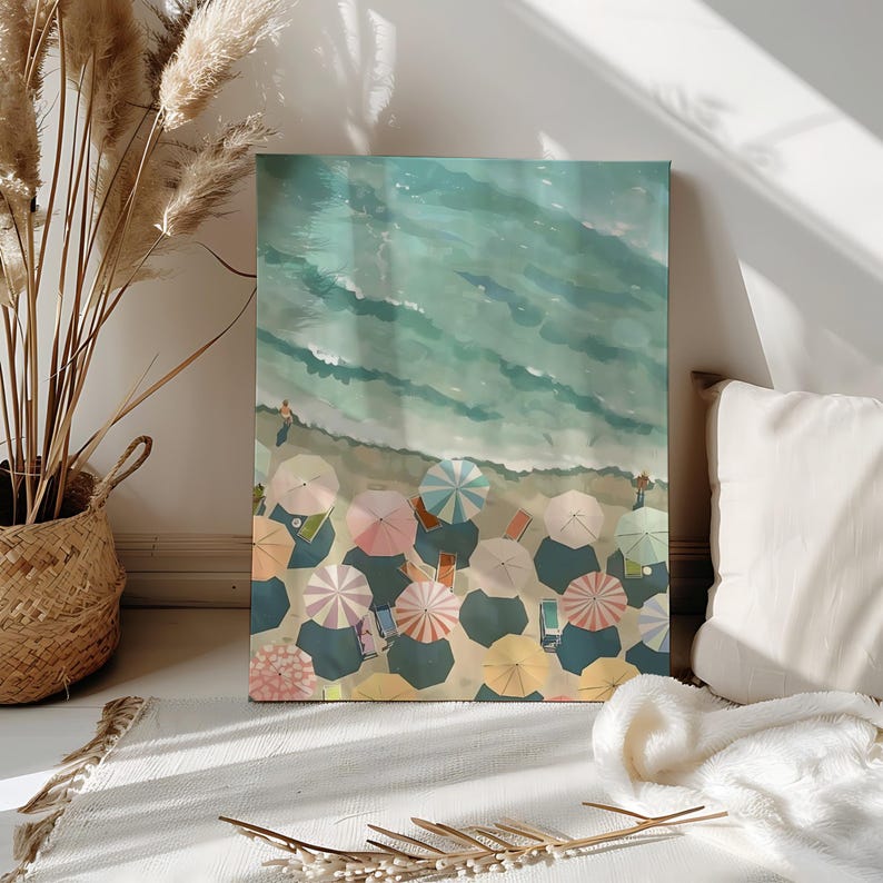 May include: An artistic canvas print depicts a beach scene from a high angle. The artwork showcases the ocean's turquoise waves meeting a sandy shore dotted with colorful beach umbrellas. The umbrellas are in shades of pink, yellow, and blue.