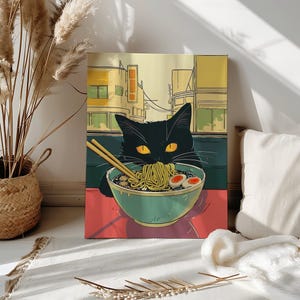 Peut inclure: Impression sur toile d'un chat noir aux yeux jaunes mangeant des nouilles ramen dans un bol turquoise. Le chat est devant un paysage urbain avec des bâtiments jaunes et verts. Baguettes dans le bol. Fond rouge et vert.