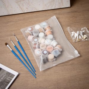 May include: Paint-by-numbers kit with small paint pots in a clear plastic bag, three paintbrushes with blue handles, and a small bag of hardware. The paint pots are numbered and contain various colors.