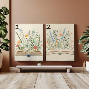 May include: Two canvas art prints featuring open books with colorful wildflowers. The artwork showcases a variety of blooms in shades of yellow, orange, pink, and blue, with green foliage. The books have a blue spine and are set against a cream background.