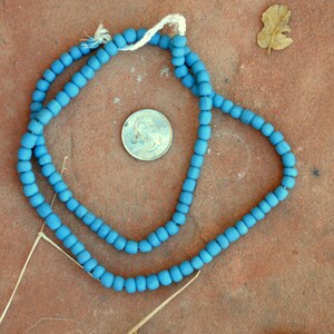 May include: A strand of blue wooden beads, approximately the size of a US quarter, strung on a white cord.