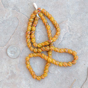 May include: A strand of orange and black striped glass beads. The beads are round and have a glossy finish.