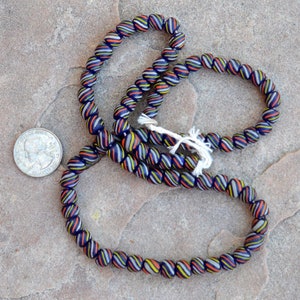 May include: A strand of blue glass beads with white, yellow, and orange stripes. The beads are round and have a glossy finish.
