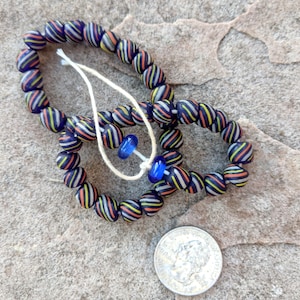 May include: A necklace made of black, white, and orange striped glass beads with two blue glass beads as accents.