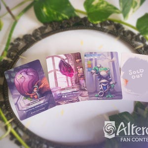 May include: Four trading cards are displayed, featuring fantasy art and text. One card shows a purple orb with a small figure, another depicts a scene with a pink crystal, and a third features a green and blue character. The fourth card reads "SOLD OUT".