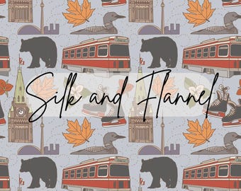 May include: A seamless pattern featuring Canadian icons in a light blue background. The pattern includes red and white maple leaves, red and white Canadian flags, red and white streetcars, black bears, a red and white ice skate, a red and white loon, and a red and white building with a clock tower. The text "Silk and Flannel" is written in black cursive.