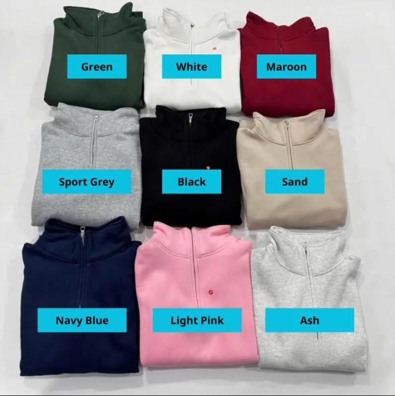 May include: Nine quarter-zip sweatshirts in various colors, including green, white, maroon, sport grey, black, sand, navy blue, light pink, and ash. Each sweatshirt has a matching label with its color name.