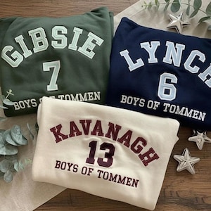 May include: Three sweatshirts in green, navy, and cream. Each features a name and number in a collegiate style. The green sweatshirt says "GIBSIE 7", the navy one says "LYNCH 6", and the cream one says "KAVANAGH 13". All have "BOYS OF TOMMEN" below.