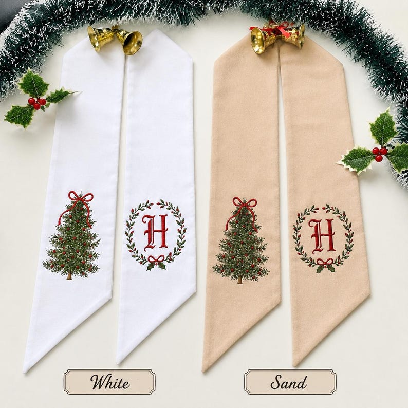 May include: Two pairs of long fabric ribbons in white and sand colors. Each ribbon features an embroidered green Christmas tree with a red bow or a red letter H inside a green wreath. Gold-colored metal bells are attached to the top of each pair.