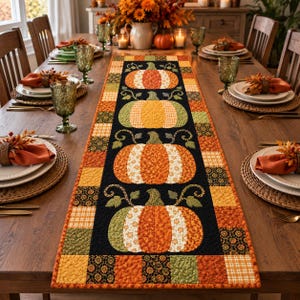 Può includere: Un runner da tavola trapuntato rettangolare con un pannello centrale nero decorato da quattro zucche applicate nei toni dell'arancione, giallo e verde. Il bordo è composto da un patchwork di tessuti autunnali con motivi arancioni, gialli e neri.