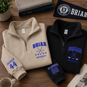 May include: Two quarter-zip sweatshirts, one tan and one black, with the word "Briar" in blue, crossed hockey sticks, and "University" printed below. The tan sweatshirt has "Graham 44" on the sleeve, and the black one has "Di Laurentis 66".