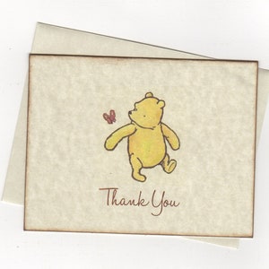 May include: A thank you card featuring a cartoon illustration of Winnie the Pooh walking with a butterfly. The card has a brown border and the text "Thank You" is printed in brown.