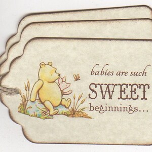 May include: Three beige paper tags with a brown border and scalloped edges. The tag features a Winnie the Pooh illustration with Piglet. The text on the tag reads "babies are such SWEET beginnings..."