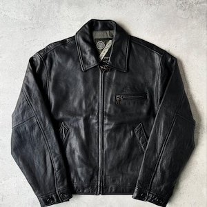 May include: Black leather jacket with a collared neckline, a front zipper, and a small chest pocket. The jacket has a classic design with buttoned cuffs and a subtle logo near the collar. The jacket is a versatile outerwear piece.