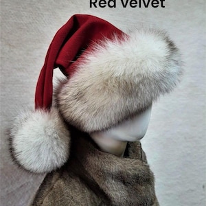 May include: A red velvet Santa hat with a white fur trim and a matching pom-pom. The hat is displayed on a mannequin head, with the text "Red velvet" visible in the image. The hat is part of a winter holiday theme.