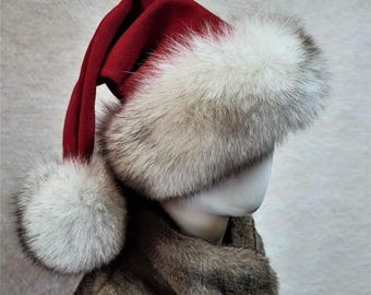 May include: A red velvet Santa hat with a white fur trim and a matching pom-pom. The hat is displayed on a mannequin head, with the text "Red velvet" visible in the image. The hat is part of a winter holiday theme.