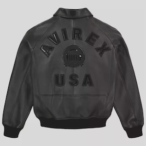 May include: Black leather bomber jacket with a collar and ribbed cuffs. The back features the text "AVIREX USA" in raised, black lettering, with a circular emblem in the center. The jacket has a classic, timeless design.