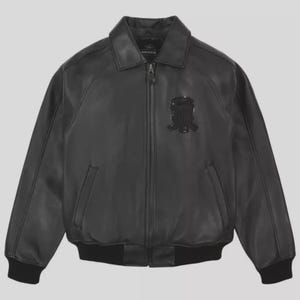 K&ouml;nnte beinhalten: Schwarze Lederjacke mit Rei&szlig;verschluss, Kragen und Aufn&auml;her auf der Brust. Die Jacke hat zwei Vordertaschen sowie gerippte B&uuml;ndchen und Saum. Der Markenname "AVIREX" ist am Kragen sichtbar.