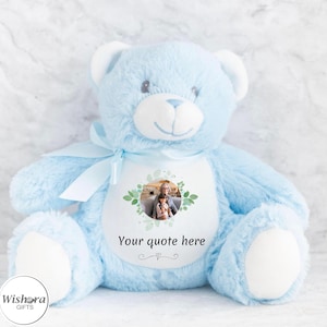 Könnte beinhalten: Hellblauer Plüschteddybär mit weißem Bauch, mit einem Foto und dem Text "Your quote here". Der Bär hat ein hellblaues Band und ein lächelndes Gesicht. Ein personalisiertes Geschenk.