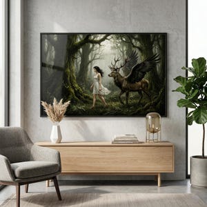 Puede incluir: Una impresión artística enmarcada representa a una mujer con un vestido blanco caminando por un bosque místico hacia un ciervo alado. La obra de arte presenta un entorno oscuro y atmosférico con exuberante vegetación y una sensación de fantasía. La impresión se muestra encima de un mueble de madera.