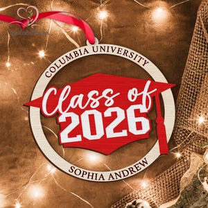 May include: A wooden Columbia University graduation ornament. The ornament features a red mortarboard shape with "Class of 2026" in white script. The name "Sophia Andrew" is below. A red ribbon is attached for hanging.