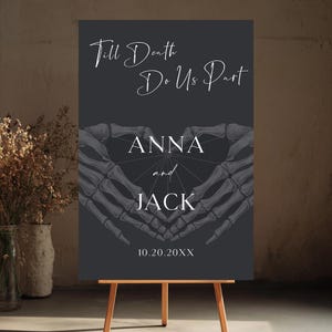 May include: A rectangular dark gray wedding sign featuring the white text Till Death Do Us Part, the names ANNA and JACK, and the date 10.20.20XX. The design includes a central illustration of two skeleton hands forming a heart shape over a spiderweb.