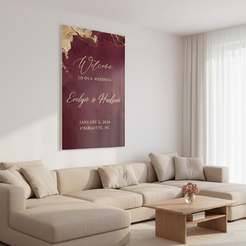 May include: A vertical rectangular wedding welcome sign featuring a deep burgundy background with gold marble-like accents at the top. The text reads Welcome to our wedding, Evelyn & Hudson, January 3, 2026, Charlotte, NC in gold script and print.