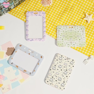 May include: Four ID badge holders in various designs. One is lavender with bows, another is light green with small illustrations, a third is light blue with bears, and the last is off-white with food illustrations.