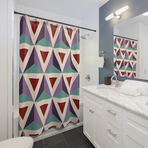 May include: A shower curtain featuring a repeating geometric pattern of triangles in shades of deep red, purple, teal, and cream. The fabric hangs from a black rod with metal rings, displaying a structured, multi-colored design across the surface.