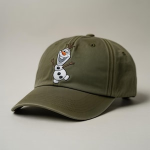 May include: Olive green baseball cap featuring an embroidered Olaf from Frozen. The cap has a curved brim and an adjustable strap. Olaf is depicted with a smiling face, carrot nose, and stick arms.