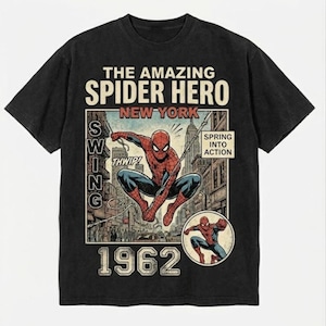 Pode incluir: Camiseta preta com um gr&aacute;fico de banda desenhada vintage do Homem-Aranha a balan&ccedil;ar-se em Nova Iorque. O design inclui o texto "The Amazing Spider Hero New York" e "1962". A camisa tem um aspeto envelhecido.
