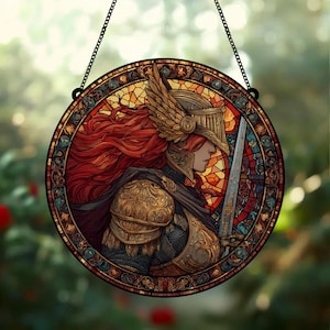 May include: Round stained glass window art featuring a warrior in golden armor, a winged helmet, and flowing red hair. The warrior holds a sword. The artwork is framed with a decorative border and hangs from a black chain.