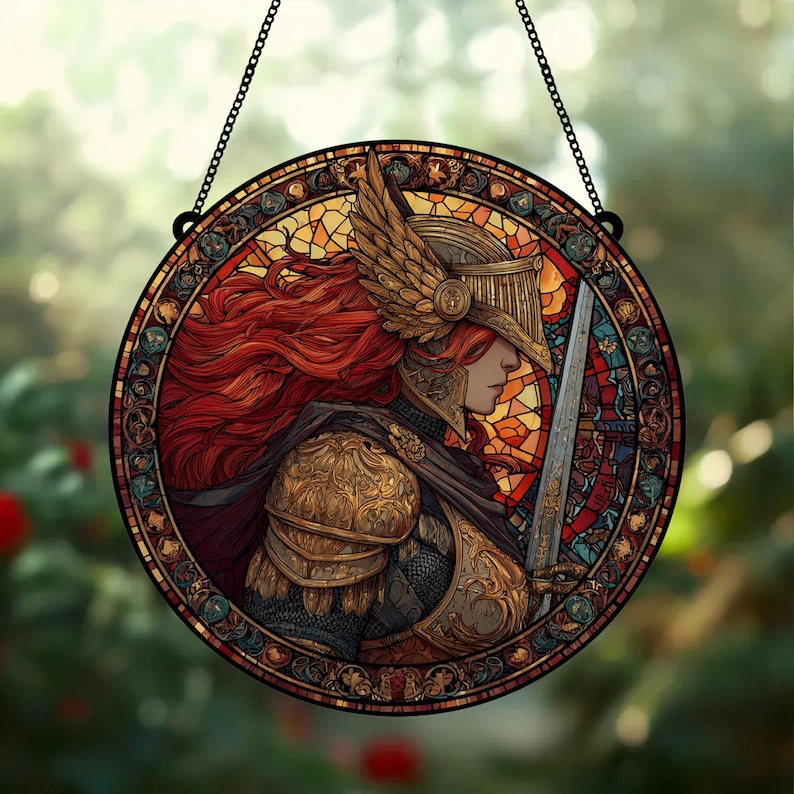 May include: Round stained glass window art featuring a warrior in golden armor, a winged helmet, and flowing red hair. The warrior holds a sword. The artwork is framed with a decorative border and hangs from a black chain.