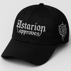 Puede incluir: Gorra de béisbol negra con texto bordado blanco "Astarion (approves)" en la parte delantera y un diseño circular blanco en el lateral. La gorra tiene una visera curva y un botón.