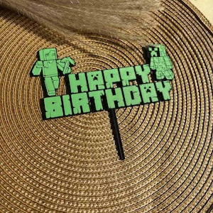 Puede incluir: Topper de pastel verde con un personaje de Minecraft con las palabras "Happy Birthday" en letras verdes de bloques.