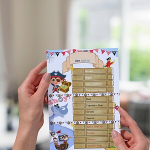 Puede incluir: Un horario con temática pirata con el texto "EGY NAPJA" en la parte superior. El diseño incluye ilustraciones de piratas, un cofre del tesoro y un tiburón. El horario lo sostiene una persona.