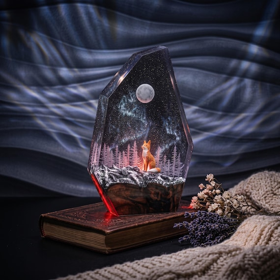 A fox frozen mid-moment inside a glowing epoxy resin snow-mountain diorama — part sculpture, part night light, entirely hand-poured.