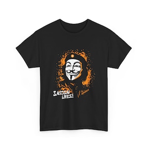 May include: Black t-shirt featuring a graphic of the Guy Fawkes mask with orange splatter and the text "Satoshi Lives!". The mask has a bitcoin symbol on the beret. The shirt is a crew neck.