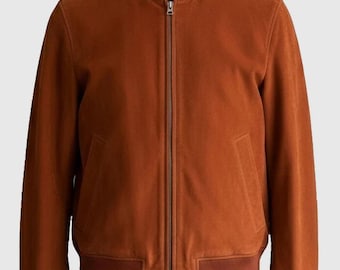 May include: A burnt orange suede bomber jacket with a stand-up collar and a full-length zipper. The jacket features two front pockets and ribbed cuffs and hem. The jacket is a classic style.