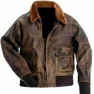 May include: A brown leather bomber jacket with a fur collar. The jacket has two front pockets with button closures, a zipper closure, and ribbed cuffs and hem. The leather has a distressed appearance.