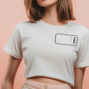 May include: White t-shirt featuring a black ticket graphic on the chest. The ticket design includes a barcode and a perforated edge. The shirt has short sleeves and a crew neck, suitable for casual wear.