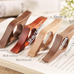 Puede incluir: Cuatro sujetap&aacute;ginas de madera en nogal negro, nogal rojo, haya y una madera m&aacute;s oscura. Los soportes miden 8,5 cm y 8,7 cm de largo, con un orificio para el dedo de 2,2 cm. El texto de la imagen dice "Estilo A" y "Estilo B".