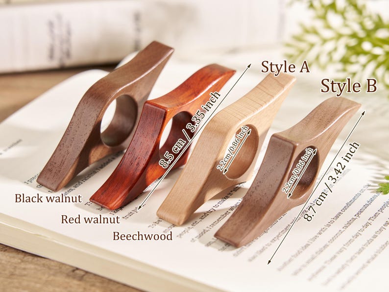 Puede incluir: Cuatro sujetap&aacute;ginas de madera en nogal negro, nogal rojo, haya y una madera m&aacute;s oscura. Los soportes miden 8,5 cm y 8,7 cm de largo, con un orificio para el dedo de 2,2 cm. El texto de la imagen dice "Estilo A" y "Estilo B".