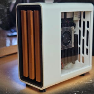May include: A white computer case with a rectangular design. The front features three vertical, brown, rectangular vents. The side has a series of vertical slots. The interior components include a fan and a heat sink.