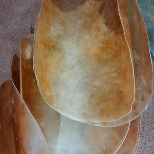 May include: A stack of translucent, irregularly shaped, amber-coloured pieces. The pieces have a smooth, polished appearance with variations in colour and texture, suggesting a natural material.