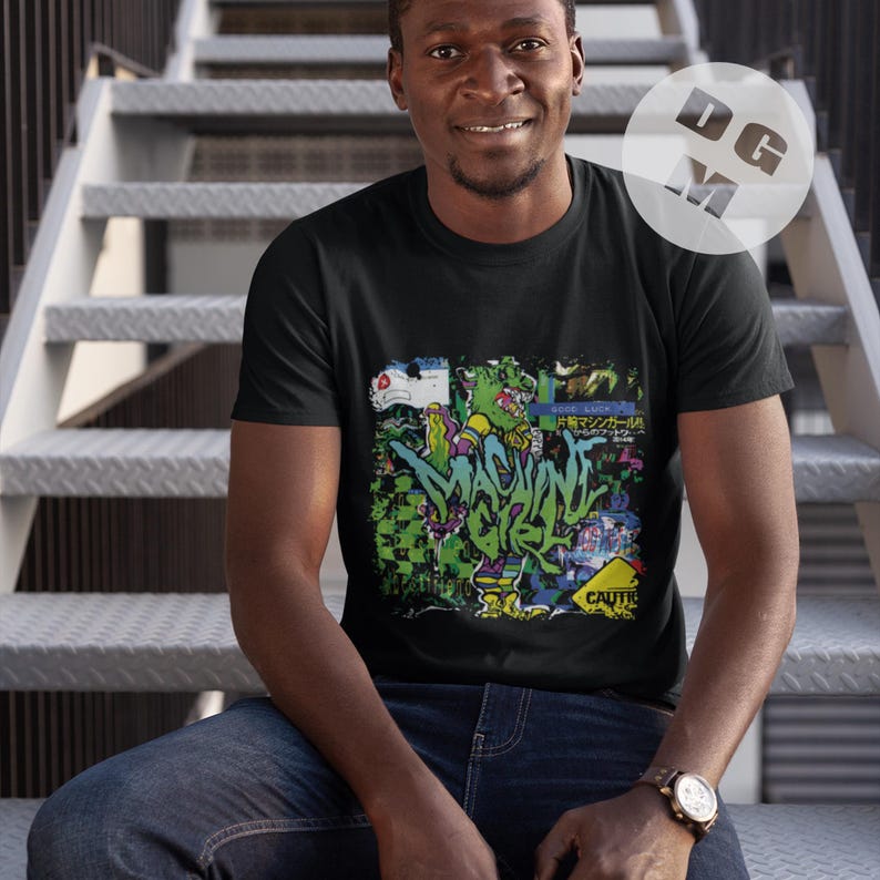 May include: A black t-shirt with a colorful graphic print of a cartoon character and the text "MACHINE GIRL".