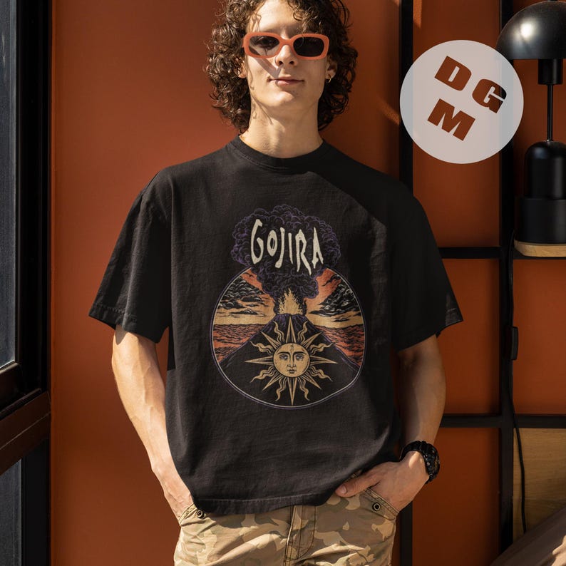 May include: Black t-shirt with a graphic of a sun and a volcano with the word "GOJIRA" printed above it.