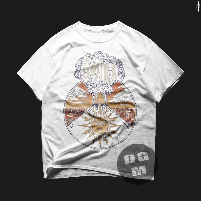 May include: White t-shirt with a graphic print of a volcano erupting with the word "GOJIRA" in the smoke cloud. The volcano is surrounded by a sun with a face and clouds. The graphic is in a circle with a brown, orange, and red background.