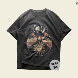 May include: A dark gray t-shirt with a graphic print of a volcano erupting with a sun and the word "GOJIRA" above it.