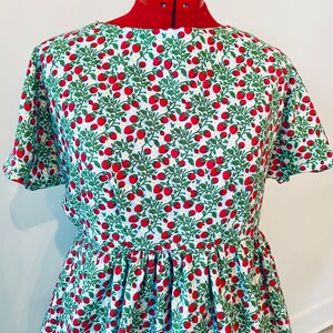 May include: A light blue dress with a strawberry print. The dress has short sleeves and a gathered skirt.